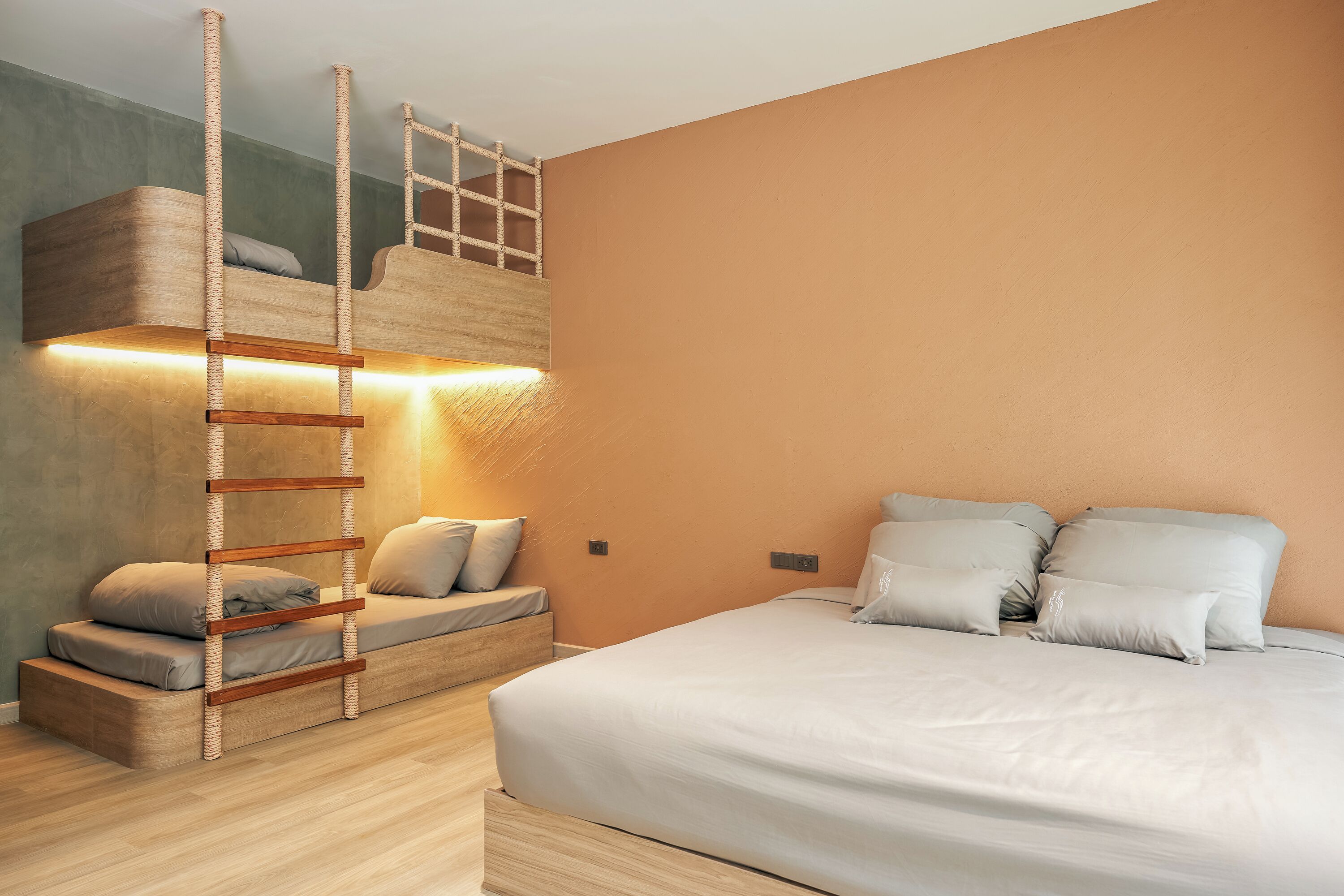 A bedroom with a bunk bed, a ladder, and a sofa.
