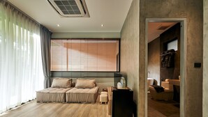 A modern living room with a sofa, ottoman, and a small table with a speaker. - Baan Rai Santisuk (Lom Sak)