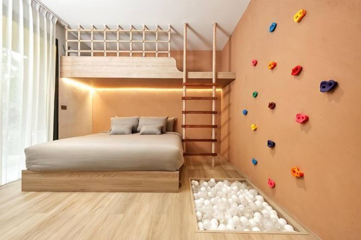 Un dormitorio con literas, una pared de escalada y una piscina de pelotas.