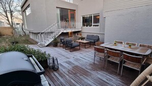 A deck with outdoor furniture, a barbecue grill, and a staircase leading to an upper level. - Luxurious Villa in Reykjavik (Reykjavík)