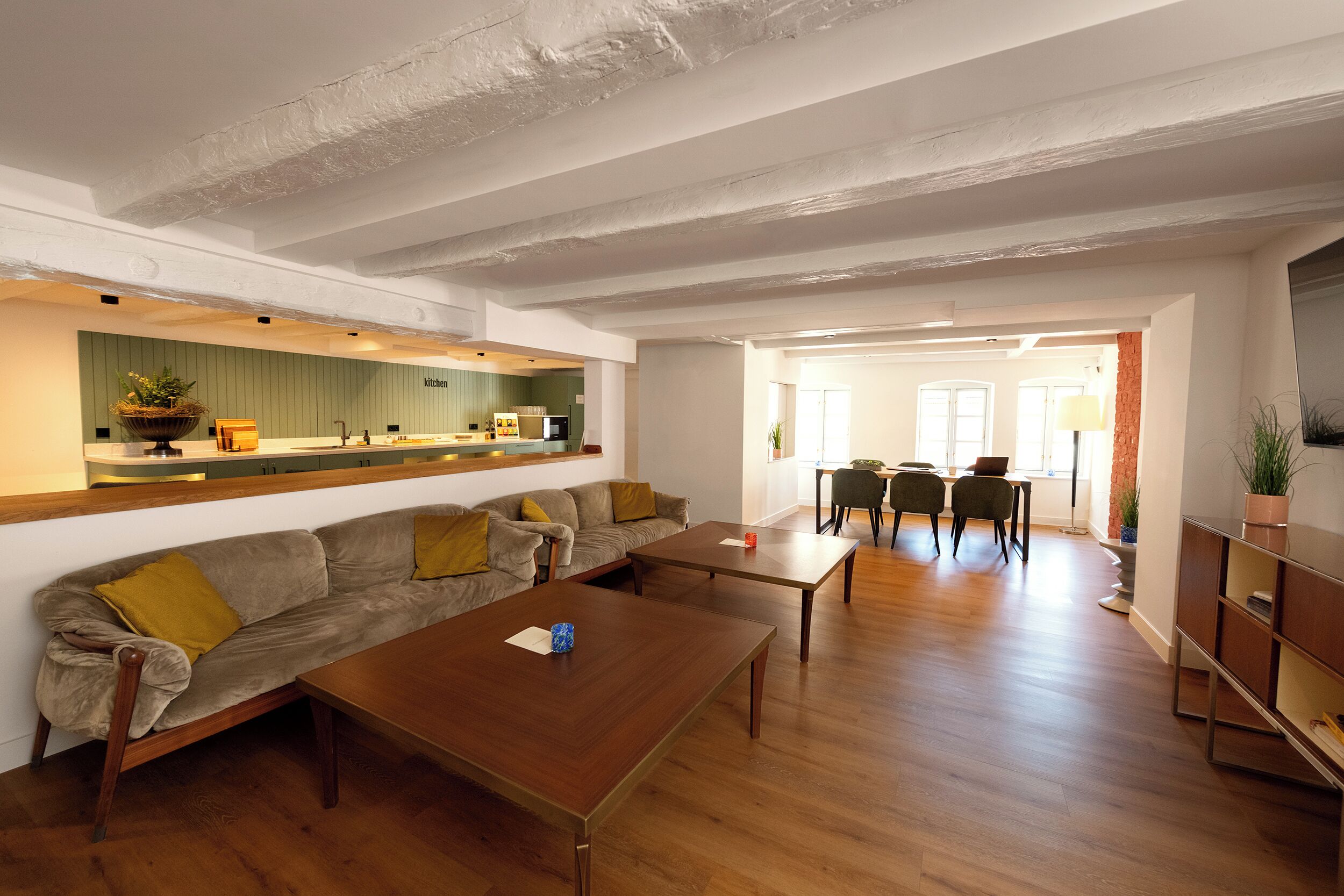 A modern living room with a sofa, coffee table, and dining area.