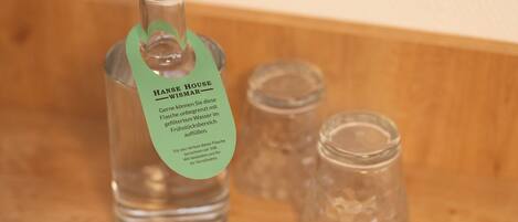 Una bottiglia d'acqua Hans Haus Wismar con etichetta verde, posizionata su una superficie in legno accanto a due piccoli vasetti di vetro.