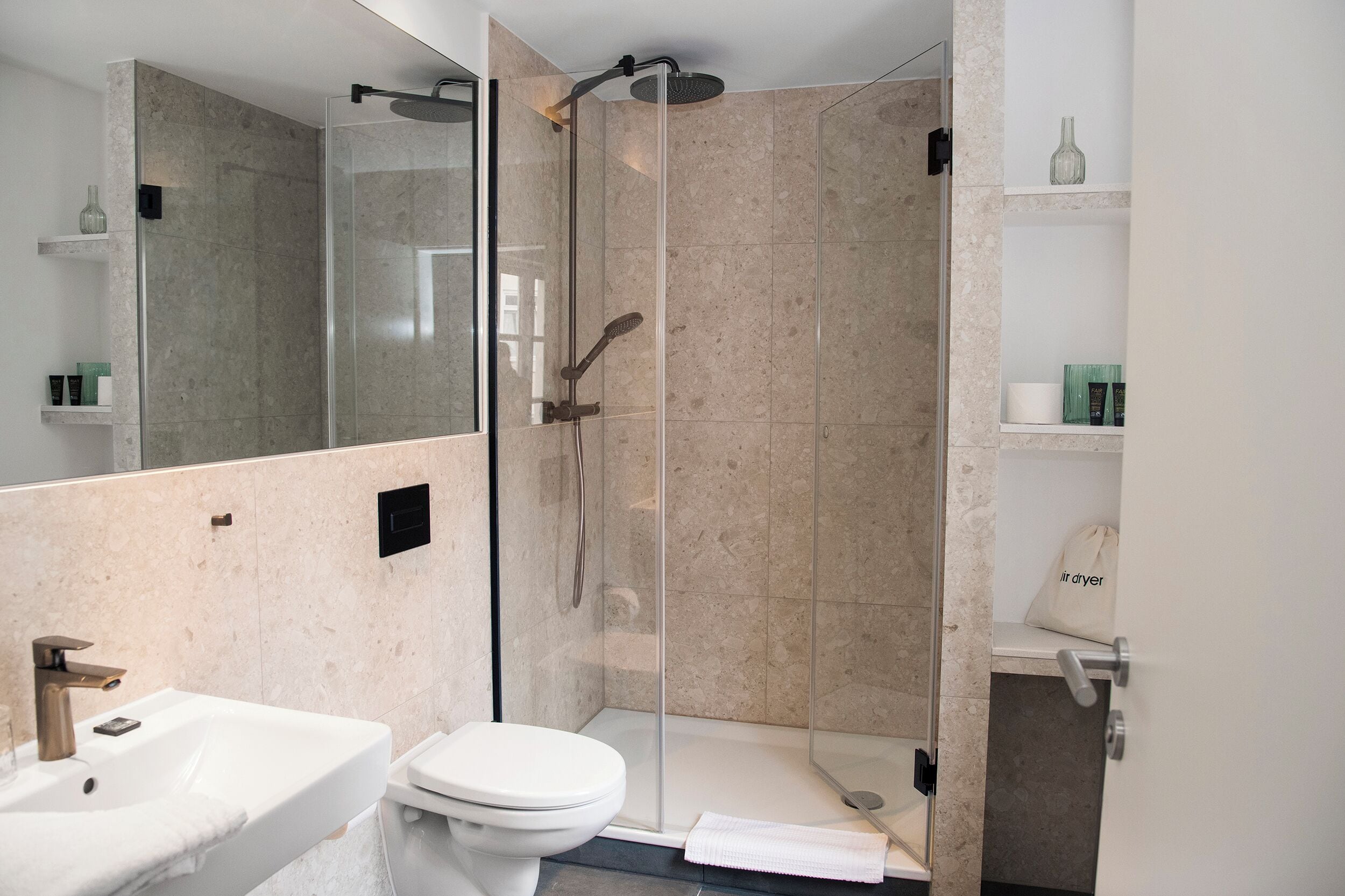 Ein modernes Badezimmer mit einer Glasdusche, einem weißen Waschbecken und einer Toilette.