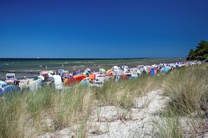 A beach with tents and beach chairs, a clear sky, and the ocean in the background. - Hanse House Wismar (Wismar)