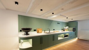 Une cuisine moderne avec des meubles de couleur verte, un plan de travail blanc et un plancher en bois.