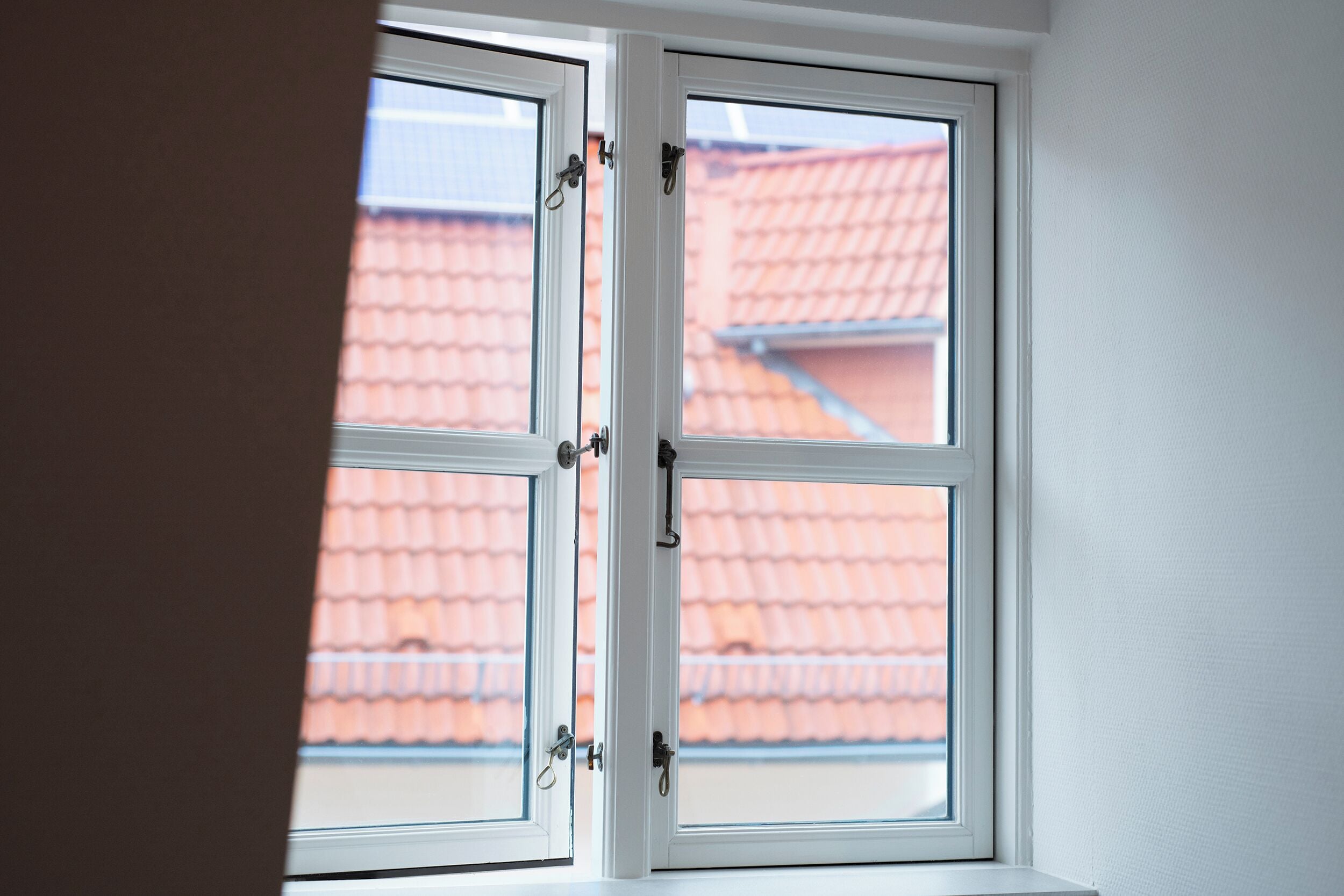 Una ventana con vista a un tejado de tejas rojas.