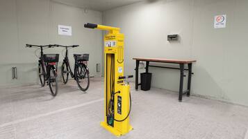 A bike rental station with two bicycles, a yellow bike pump, and a bench.