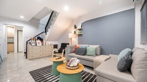 Ein modernes Wohnzimmer mit Treppe, einer Couch, einem Couchtisch und einem Beistelltisch.