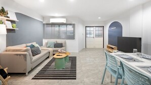 Ein modernes Wohnzimmer mit Sofa, Couchtisch und einem Essbereich mit Stühlen und Tisch.