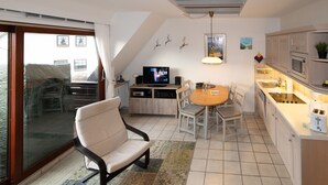 Una cocina moderna con comedor, televisor y puerta corrediza al exterior.