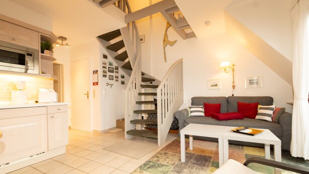 Un apartamento moderno con cocina, sala de estar y escalera.