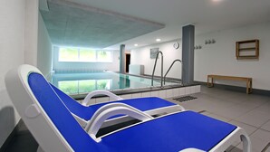 Zona de piscina con sillas de descanso, un banco y vistas a la piscina.