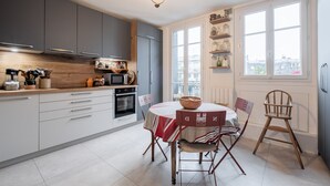 A modern kitchen with grey cabinets, a wooden countertop, and a dining area with a table and chairs.