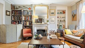A cozy living room with a fireplace, bookshelves, a sofa, and a coffee table.