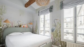 A bedroom with a bed, a window with curtains, and a wall with a plant mural. - Wood Notes, by Veeve (Paris)
