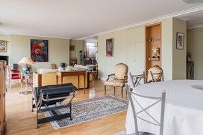 Ein geräumiges Wohnzimmer mit großem runden Tisch, einer Couch und einem Essbereich mit Holzschrank.