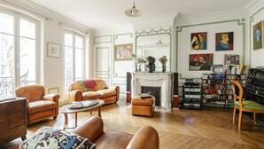 Un salon spacieux doté d’une cheminée, d’un piano et d’une bibliothèque remplie de livres et de disques.