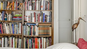 Une chambre à coucher avec une grande bibliothèque remplie de livres, un cadre de lit en bois et un oreiller rouge.