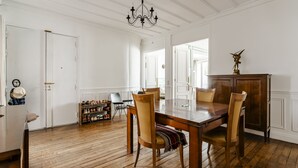 Un coin repas avec une table et des chaises en bois, un lustre et un porte-chaussures contenant des chaussures.