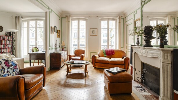 Un salon spacieux avec une cheminée, des canapés en cuir, une table basse et une bibliothèque.
