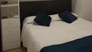 A bedroom with a bed, two pillows, a nightstand, and a wardrobe. - Beautiful two-bedroom apartment in a central location, just a few steps from the sea   (Giardini Naxos)