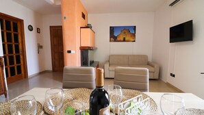 A living room with a beige sofa, a wooden door, and a wall-mounted TV.
