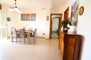 A dining area with a table, chairs, and a chandelier. There are framed pictures on the wall and a potted plant on a wooden cabinet. - Calipso's home in Otranto (Otranto)