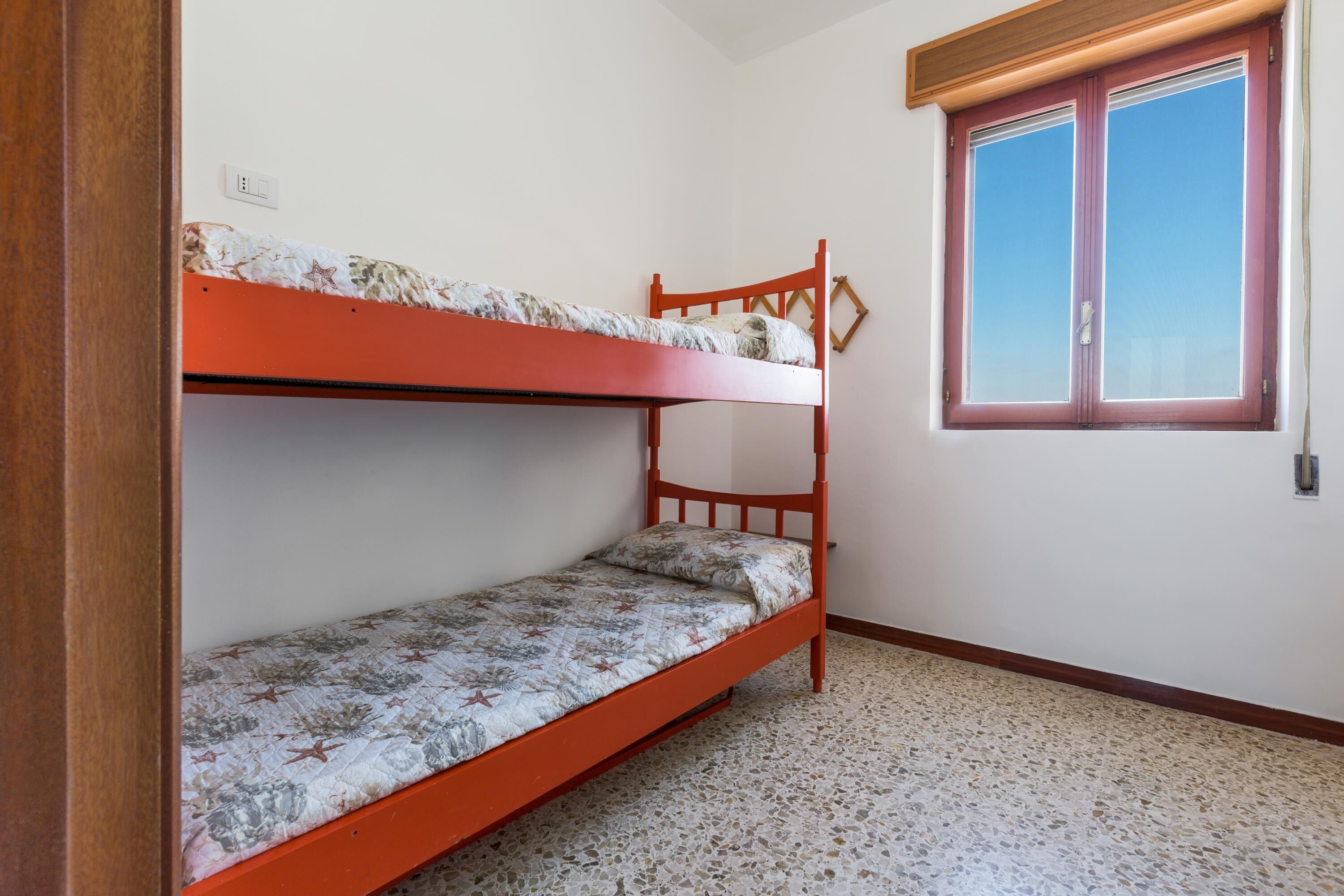 A bunk bed room with a window and a door.