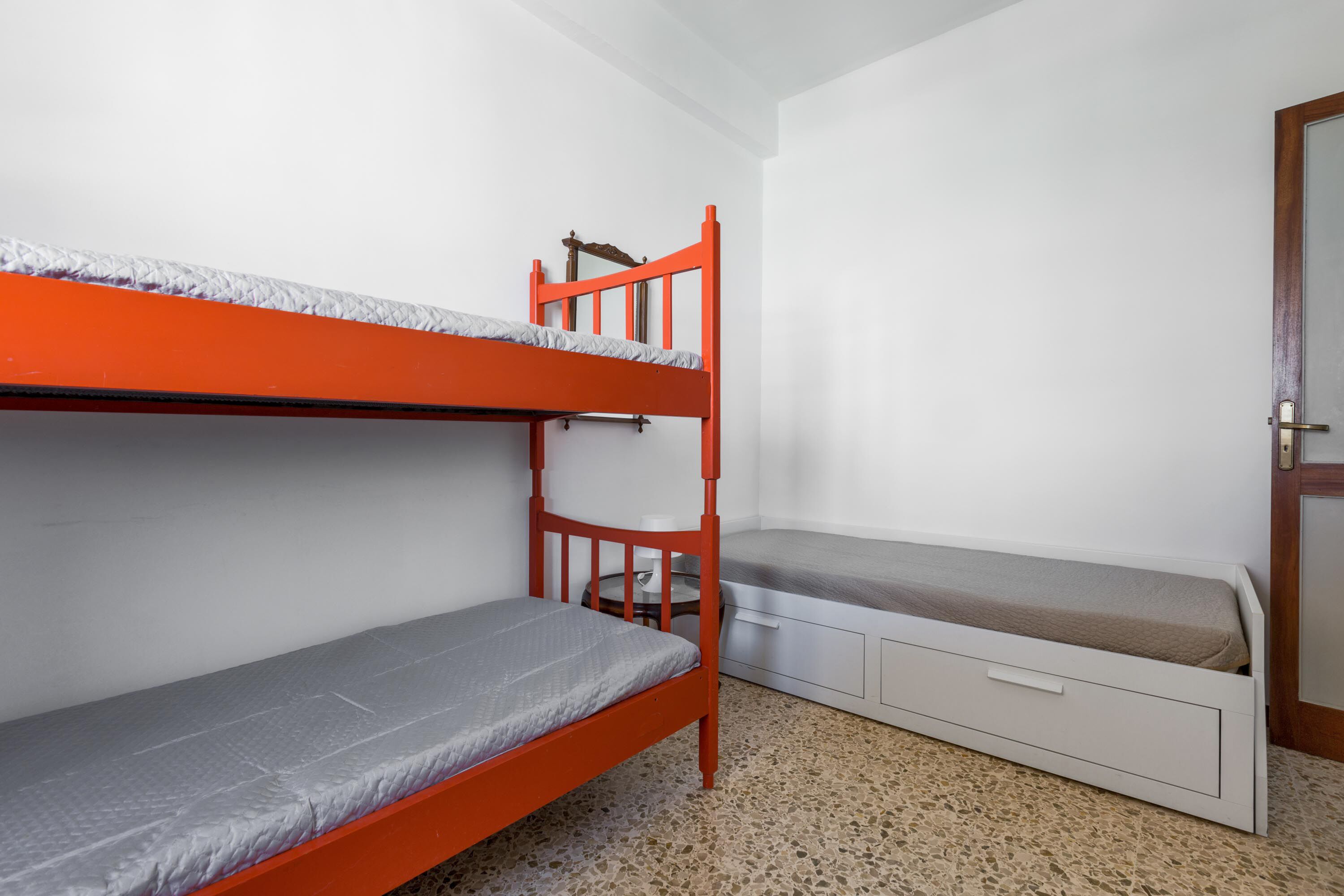 Un dormitorio con dos literas, una mesita pequeña y una cómoda.
