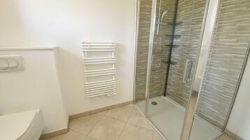 Een badkamer met toilet, een douche met glazen wanden en een witte handdoekhouder.