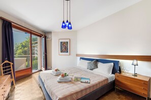 A bedroom with a bed, bedside table, and a view through a sliding door. - Comfort Holiday In Paradiso With Lake Lugano View (Paradiso)