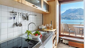 A kitchen with a view of a balcony, a sink, and a stove. - Comfort Holiday In Paradiso With Lake Lugano View (Paradiso)