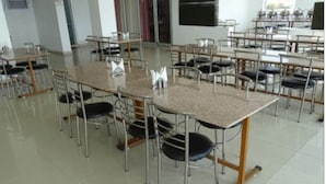 A classroom with multiple tables and chairs, arranged in rows. - Hotel Jhansla By GRB (Behror)