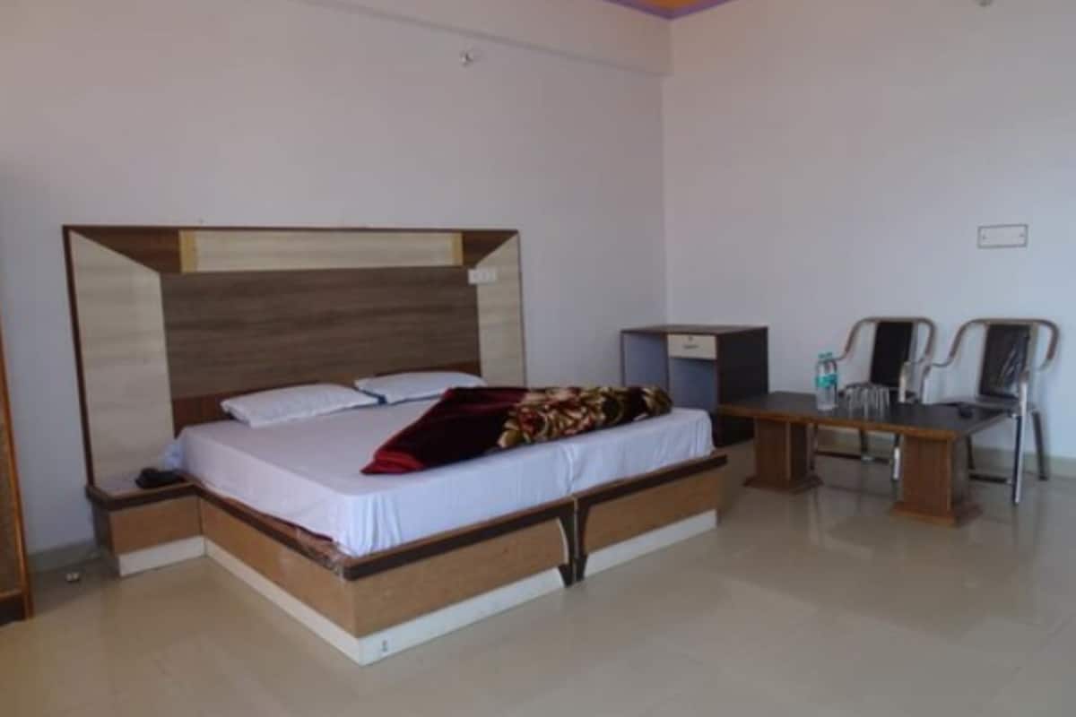A bedroom with a bed, bedside tables, a desk, and a chair.