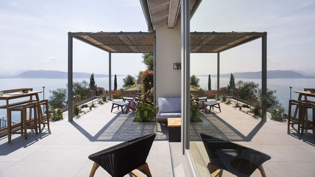 Eine Terrasse mit Sitzgelegenheiten im Freien, Blick aufs Meer und einer Pergola.