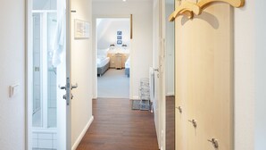 A hallway with a wooden floor leading to a bedroom with a bed and a nightstand. - Herzlich Willkommen im Appartement Meier (List auf Sylt)