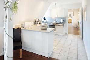 Une cuisine moderne avec des meubles blancs, un îlot central et un coin repas.