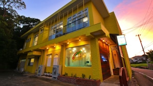 A two-story yellow building with a balcony, large windows, and a sign reading "Pension Alamo". - pension Aloalo (Shirahama)