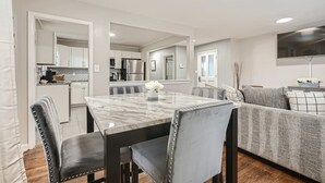 A modern kitchen with white cabinets, a marble countertop, and stainless steel appliances.