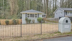 A residential house with a fenced yard, a mailbox, and a number 2323 on the mailbox.