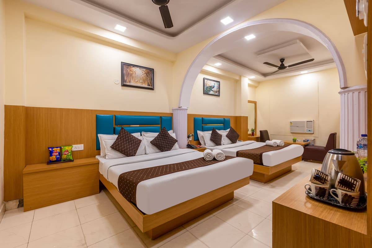A hotel room with two beds, a desk, and a seating area.