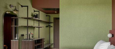 Un dormitorio con cama, espejo, estante con objetos y puerta que da a otra habitación.
