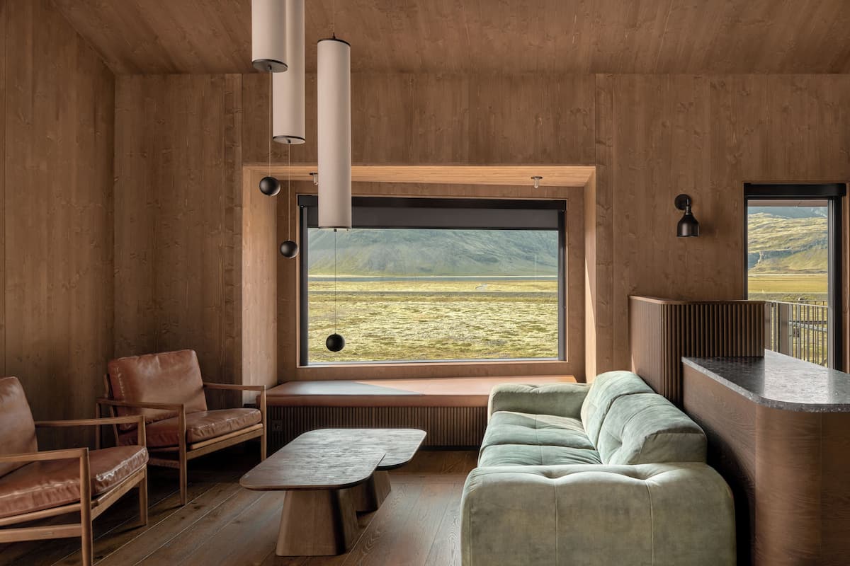 A modern interior with a large window, wooden walls, a sofa, chairs, and a small table.