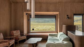 A modern interior with a large window, wooden walls, a sofa, chairs, and a small table.