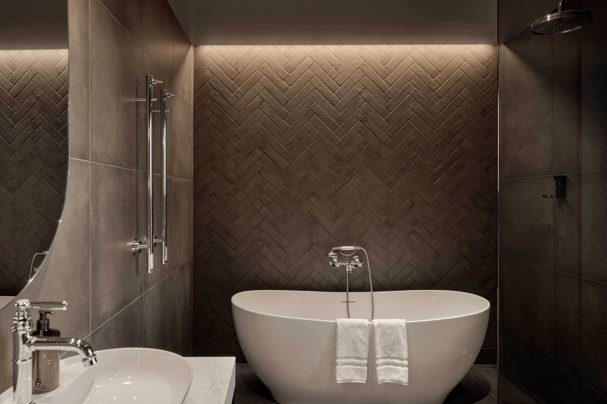 A modern bathroom with a large freestanding bathtub, a glass shower enclosure, and a vanity with a sink and mirror.