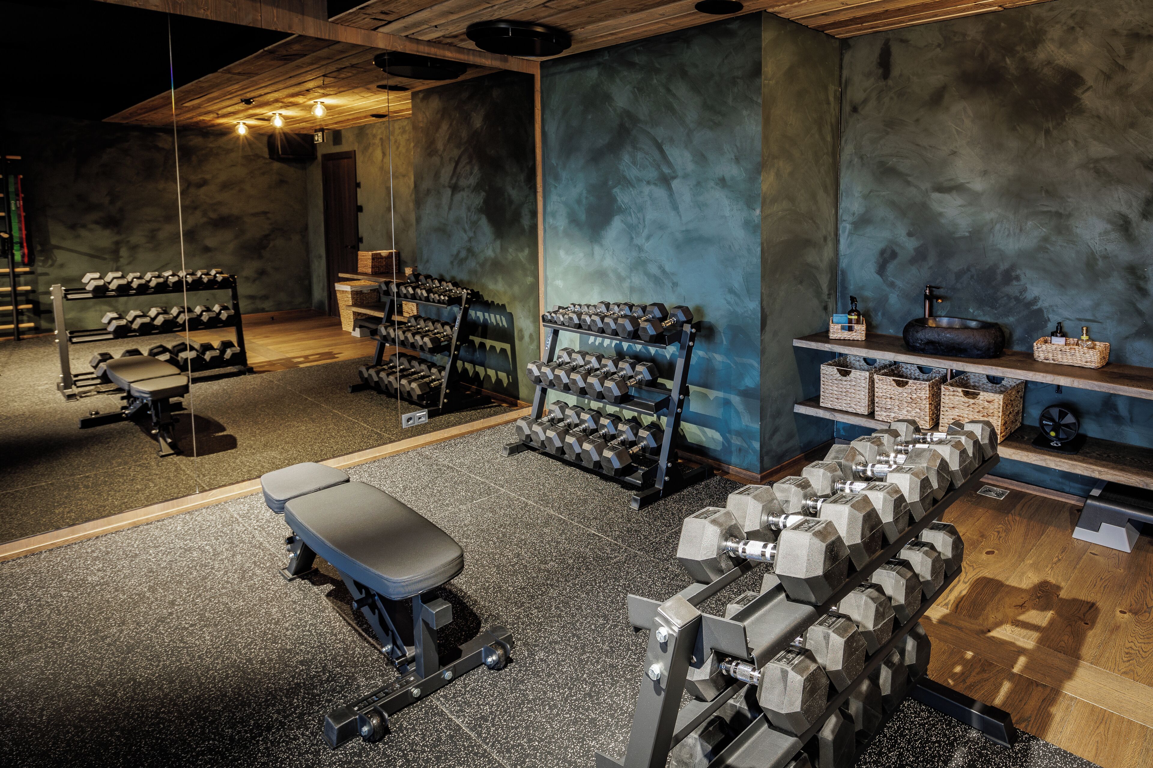 A gym with weightlifting equipment, benches, and dumbbells.
