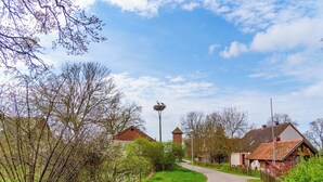 A rural road with houses on either side, a clear sky, and a lamp post in the distance. - Alandblick Inn (Wanzer)