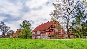 A traditional half-timbered house with a red roof, surrounded by lush green grass and trees. - Alandblick Inn (Wanzer)