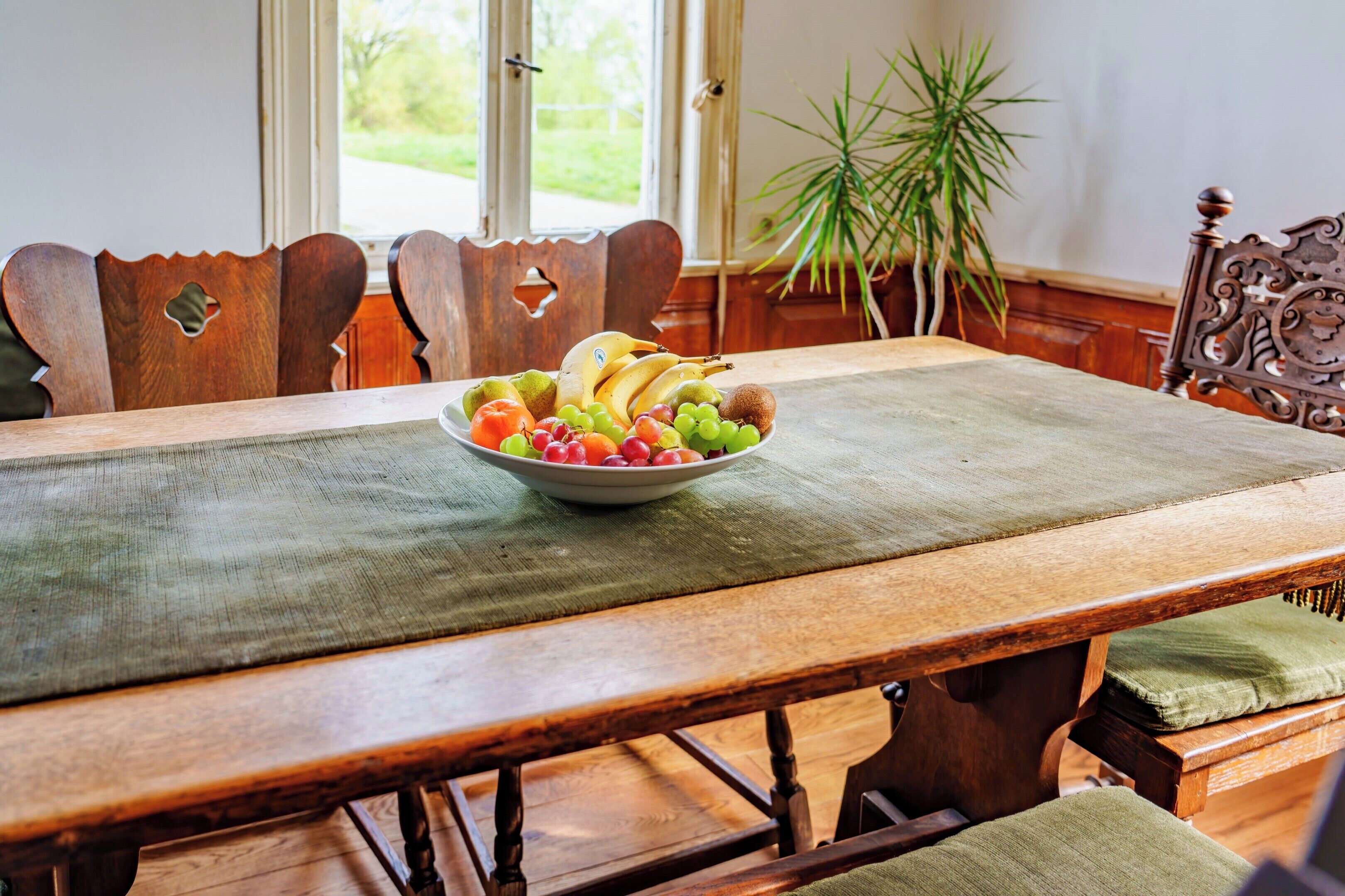 Een houten eettafel met een schaal fruit in het midden.