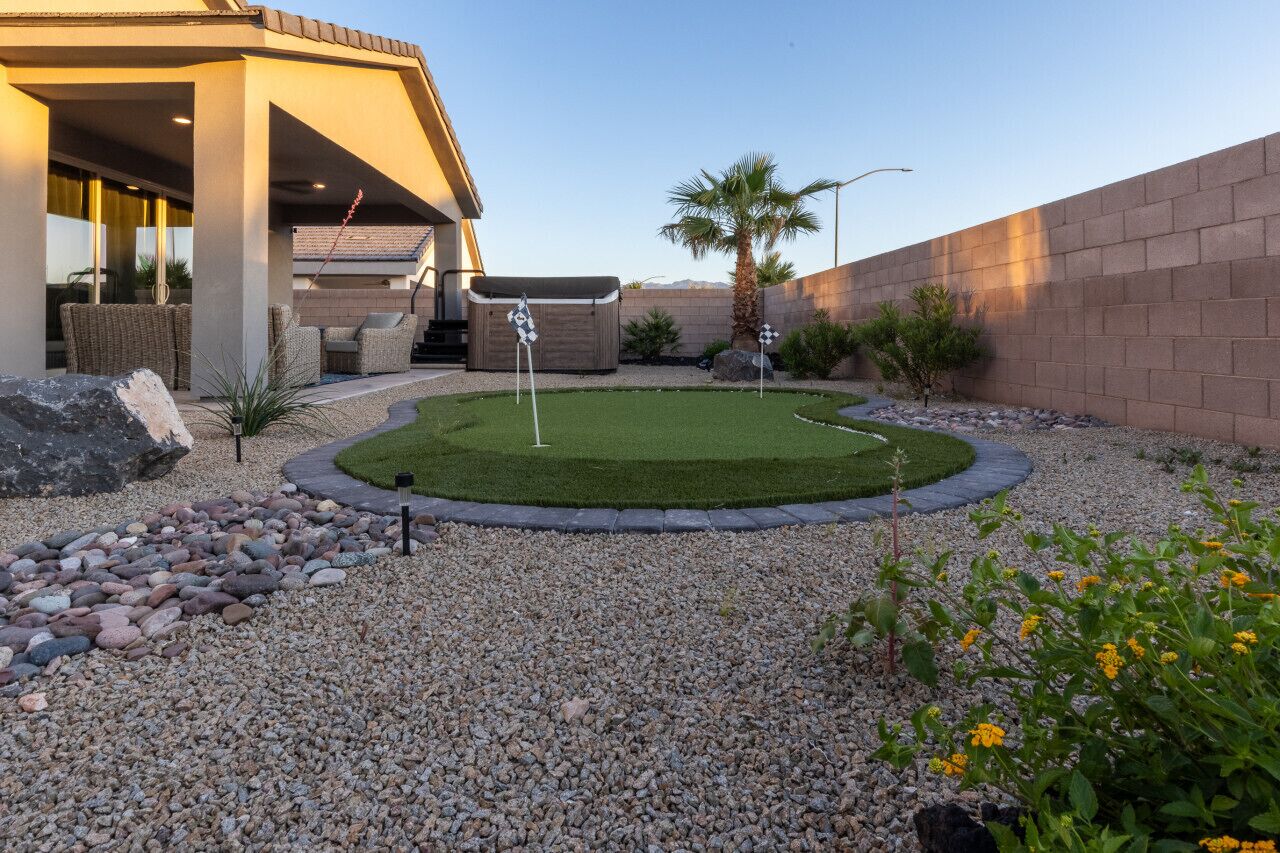 Un jardín ajardinado con un patio, una bañera de hidromasaje y una palmera.